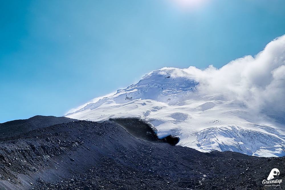 El glaciar del Antisana con nubes, visto desde el borde oscuro de un cráter