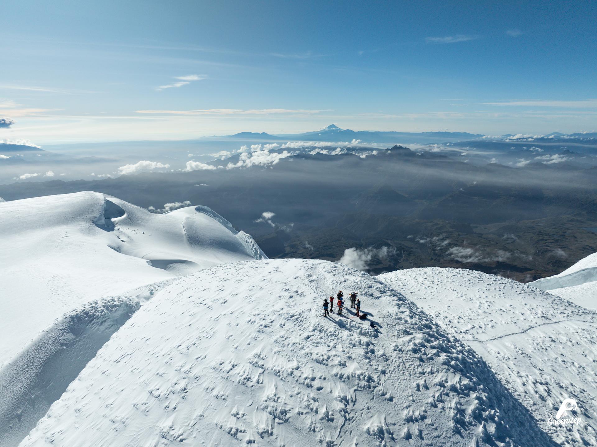 Cordada de Greenstep sobre la cumbre nevada del Cayambe, con volcanes lejanos al fondo