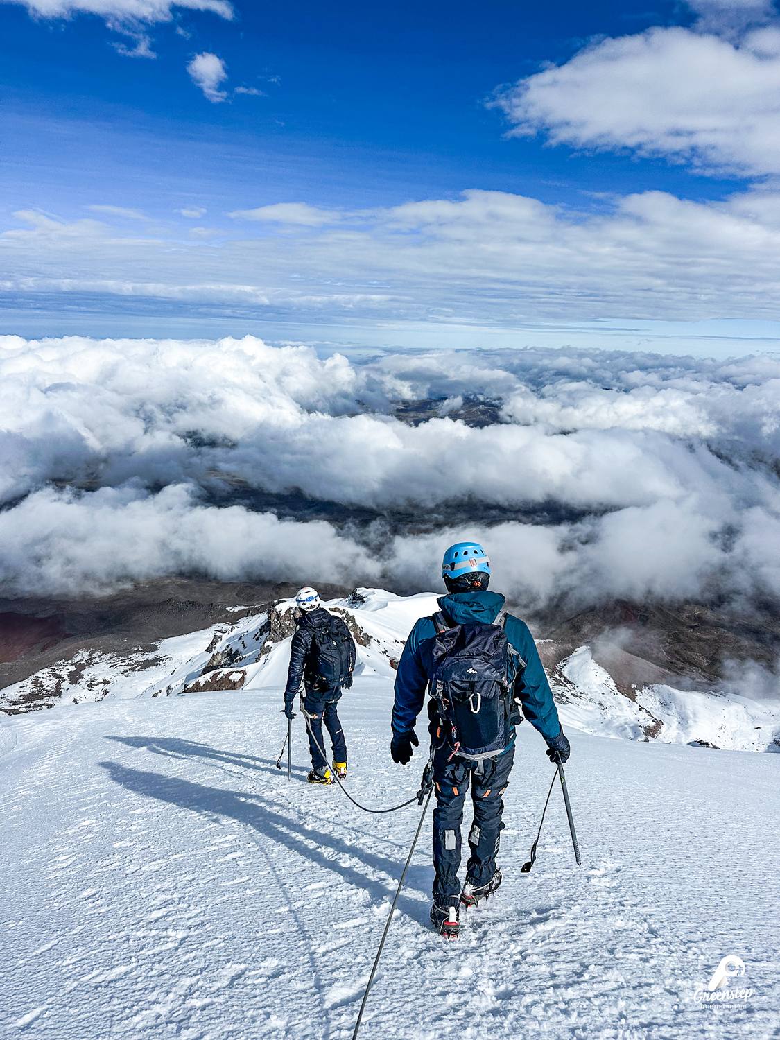 Dos montañistas encordados sobre la nieve del Chimborazo, con un mar de nubes abajo