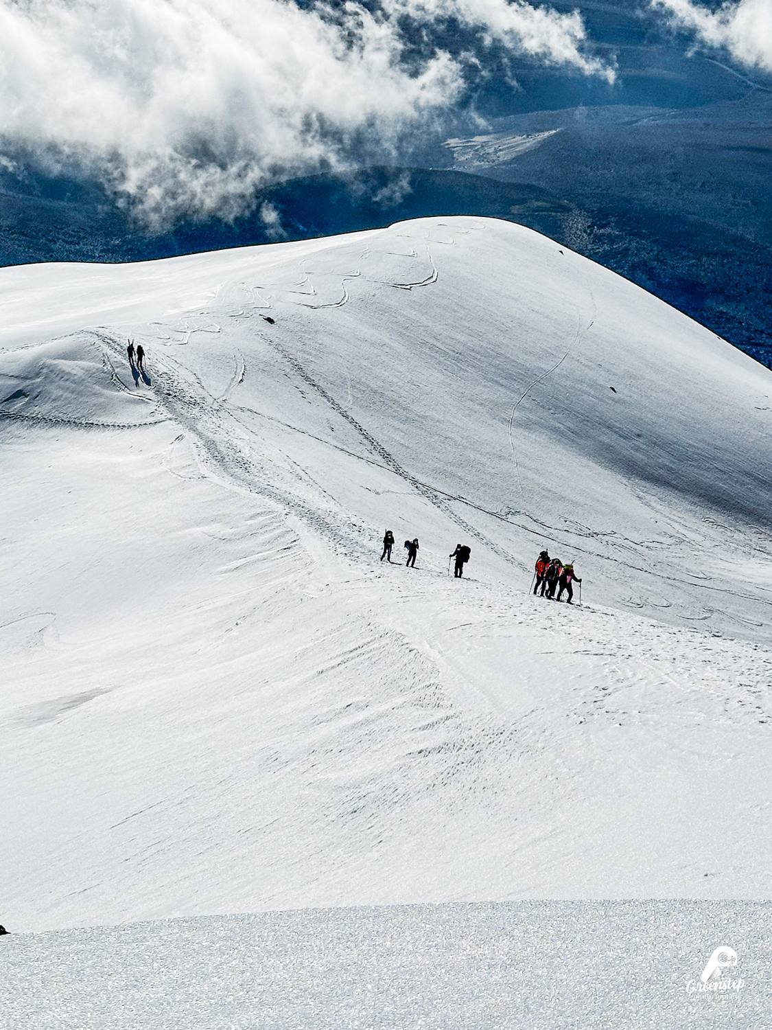 Cordada ascendiendo por la nieve del Chimborazo, con nubes al fondo
